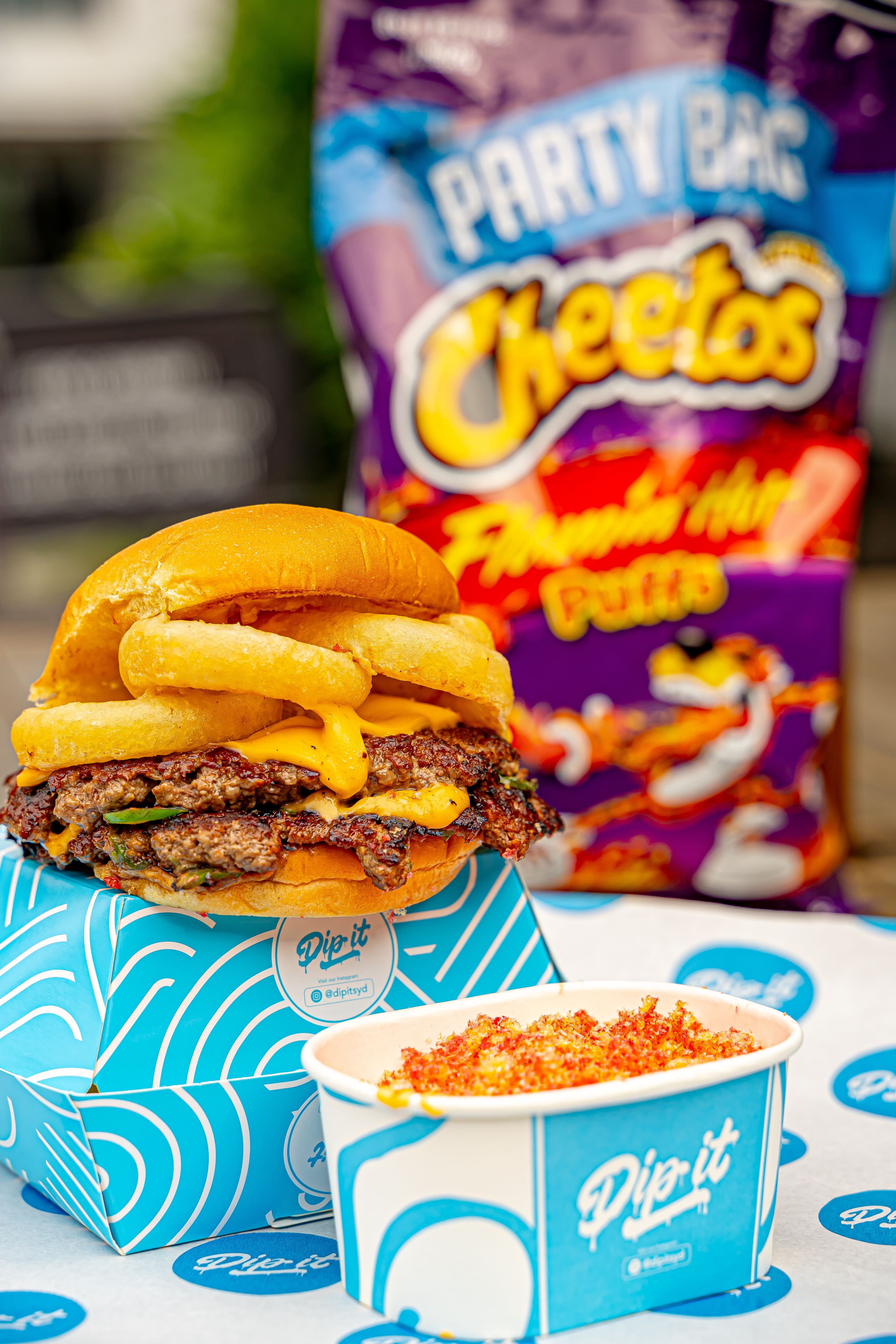 Flamin' Hot Fozball burger in Dip It box with Flamin' Hot Cheetos party bag and queso dip cup